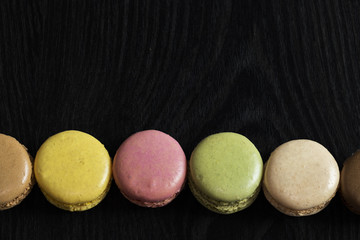 Macarons de couleurs différentes en ligne sur fond noir