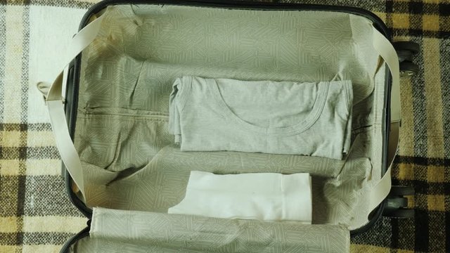 Hendheld shot: A woman is packing a suitcase. It puts things together for travel.