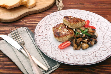 Roasted chicken cutlet with garnish with mushrooms on old wooden