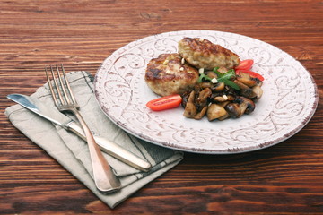 Roasted chicken cutlet with garnish with mushrooms on old wooden