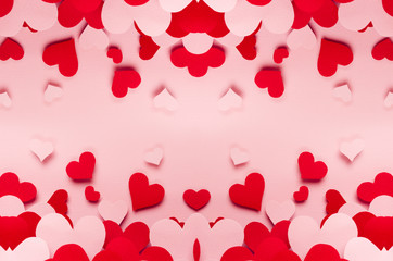 Red and pink paper hearts different size on pink background. Valentine day backdrop.
