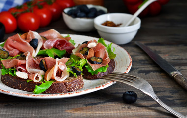 Toast of rye bread with jamon, blueberries and almonds. Snack with a proshoto!
