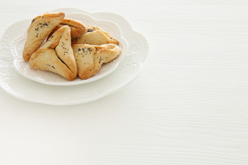 Purim celebration concept (jewish carnival holiday). Traditional hamantaschen cookies over white table.