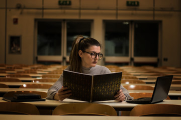 Studentessa universitaria. Studio in aula con libro, computer, notebook. Sedie in fila nella...