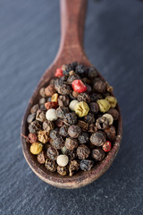 Chinese pepper, Sichuan pepper in wooden spoon on black slate stone plate