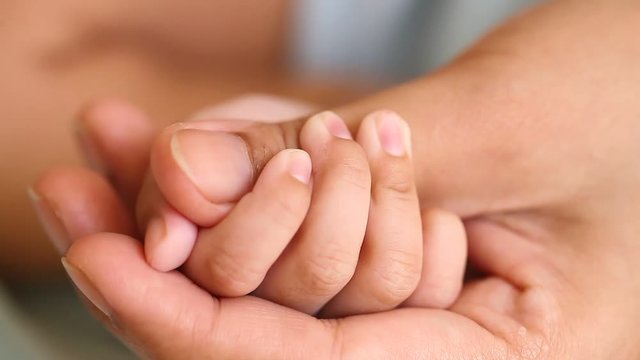 Mother holding newborn baby's hand