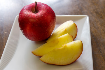 Sliced fresh red apple on a white square dish