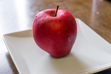 Fresh red apple on a white square dish
