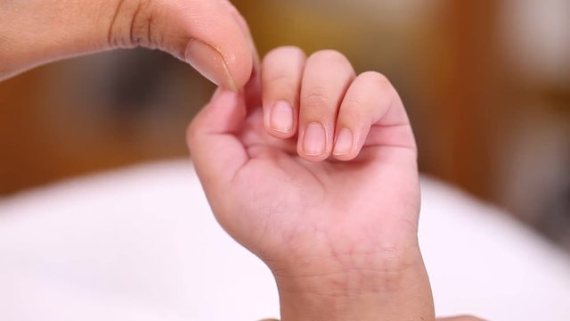 Cute newborn baby boy holding mother's finger 