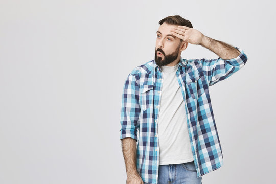 Adult bearded guy wiping his forehead with hand making phew gesture, expressing relief while standing against gray wall. Man feels happy that he prevented huge disaster. It was close enough