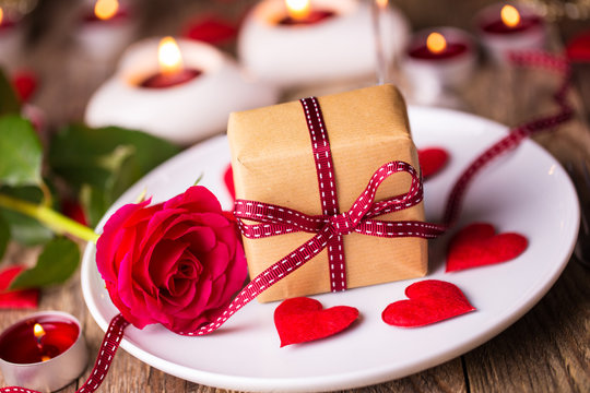 Romantic candle light dinner on Valentines Day with gift box and red rose