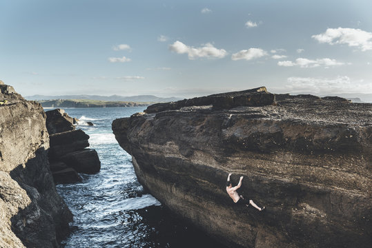 Mature climber climbing without ropes in a seacliff close to the water