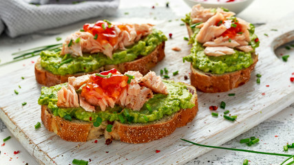 Homemade Toast sandwich with Salmon, Avocado and chilli jam on wihte wooden board. healthy food