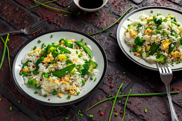Fried rice with vegetables, broccoli, peas and eggs in a plate. soy sauce. healthy food