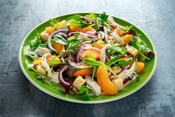 Fresh salad with chicken breast, peach, red onion, croutons and vegetables in a green plate. healthy food