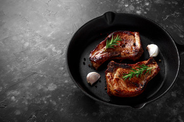 Cooked Pork Loin chops in rustic skillet, pan with rosemary. top view. background