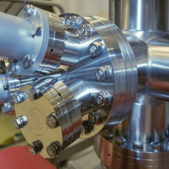 Detail of vacuum equipment featuring steel flanges and pipelines bolted to the vessel in laboratory or industrial environment.