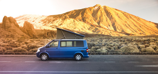 Small travel vehicle camping van or big car with folding rooftop with bed is parked under huge mountain formation. Tourism vacation and travel. Camper van and mountains landscape © gargantiopa