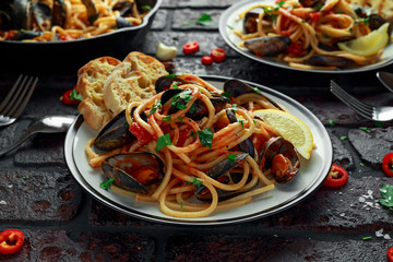 Homemade Pasta Spaghetti with mussels, tomato sauce, chilli and parsley on rustic background. sea food meal