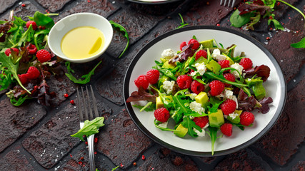 Fresh Tasty Raspberry salad with avocado, green vegetables, nuts, feta cheese, olive oil and herbs. healthy food.