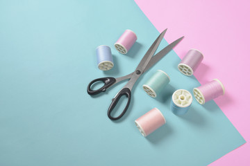 Flat lay of colored thread rolls and Scissors for sewing on two tone background, Sewing and...