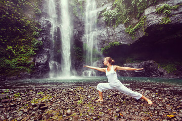 Woman practices yoga near Sekumpul waterfall in Bali, Indonesia