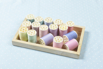 Flat lay of colored thread rolls for sewing in the wood box on blue background, Sewing and...