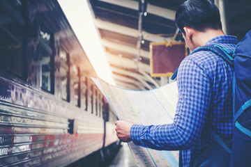 Tourist backpacker using map to travel at train station