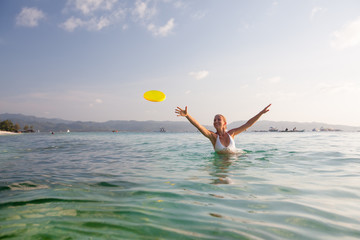 Woman plays frisbee in the water of beautiful ocean