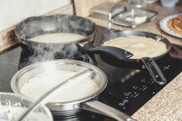 cooking pancakes in several pans