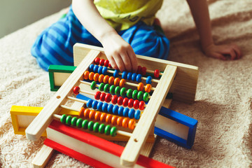 Hand of little boy playing with abacus. Clouse up picture of curly cute toddler playing with wooden toy. Children education