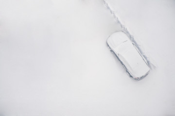 Top view on  snowy car on the parkplace at the end winter. Seasonal Snowfall