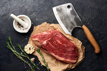 Raw fresh marbled meat Black Angus steak and meat cleaver. Meat on black background with rosemary,...
