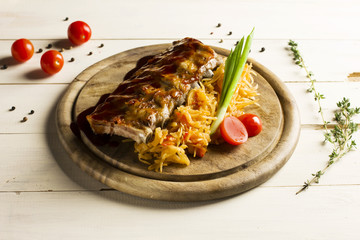 Roast ribs drizzled with sauce with stewed cabbage on a round wooden Board