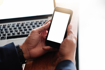 Mockup image of a man's hand holding white mobile phone with blank black desktop screen on thigh in cafe
