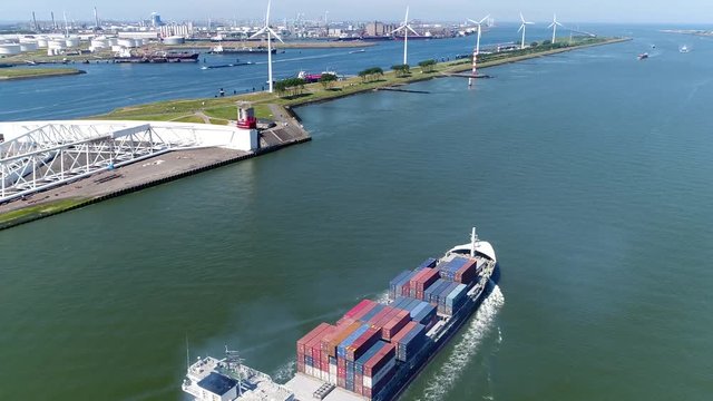 Aerial of container ship moving through Maeslantkering storm surge barrier showing heavy ship exhaust plume on Nieuwe Waterweg Netherlands barrier closes if city of Rotterdam is threatened by floods