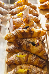 Various flavours of croissant or as in Italy their called brioche on display in a bakery in Milan, Italy with a price and sign - Albicocca means jam in Italian