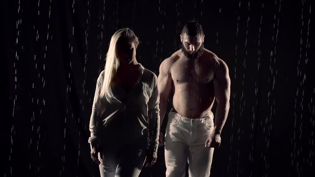 A naked man with huge muscles approaches a woman during a falling rain