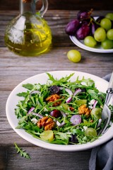 green salad bowl with arugula, walnuts, goat cheese, red onion and grapes
