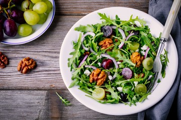 green salad bowl with arugula, walnuts, feta cheese, red onion and grapes