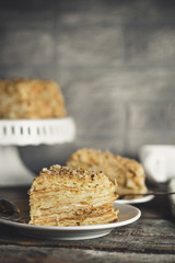 cake - Napoleon (cake with white cream is layered) and photos on a wooden table