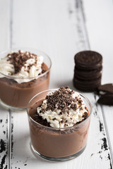 Chocolate mousse in a glasses on a white wood background.