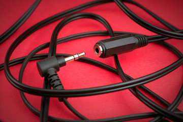 headphone wires on a red background, plug connector,  selective focus, close up