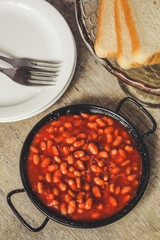 Beans in tomato sauce on a frying pan - Serving on a wooden table