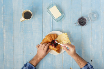 man having breakfast on wooden table at home top view