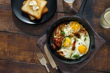 Breakfast table. Fried eggs with bacon in frying pan
