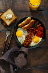 Full English breakfast on dark wooden table, top view