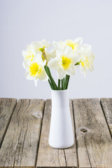 white daffodils at china vase on old weathered wood table