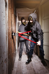 Two teenage burglars breaking in basement cellar with 30 inch bolt cutters