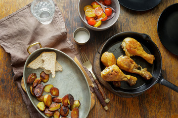 Dinner table. Fried chicken legs pan potatoes salad top view